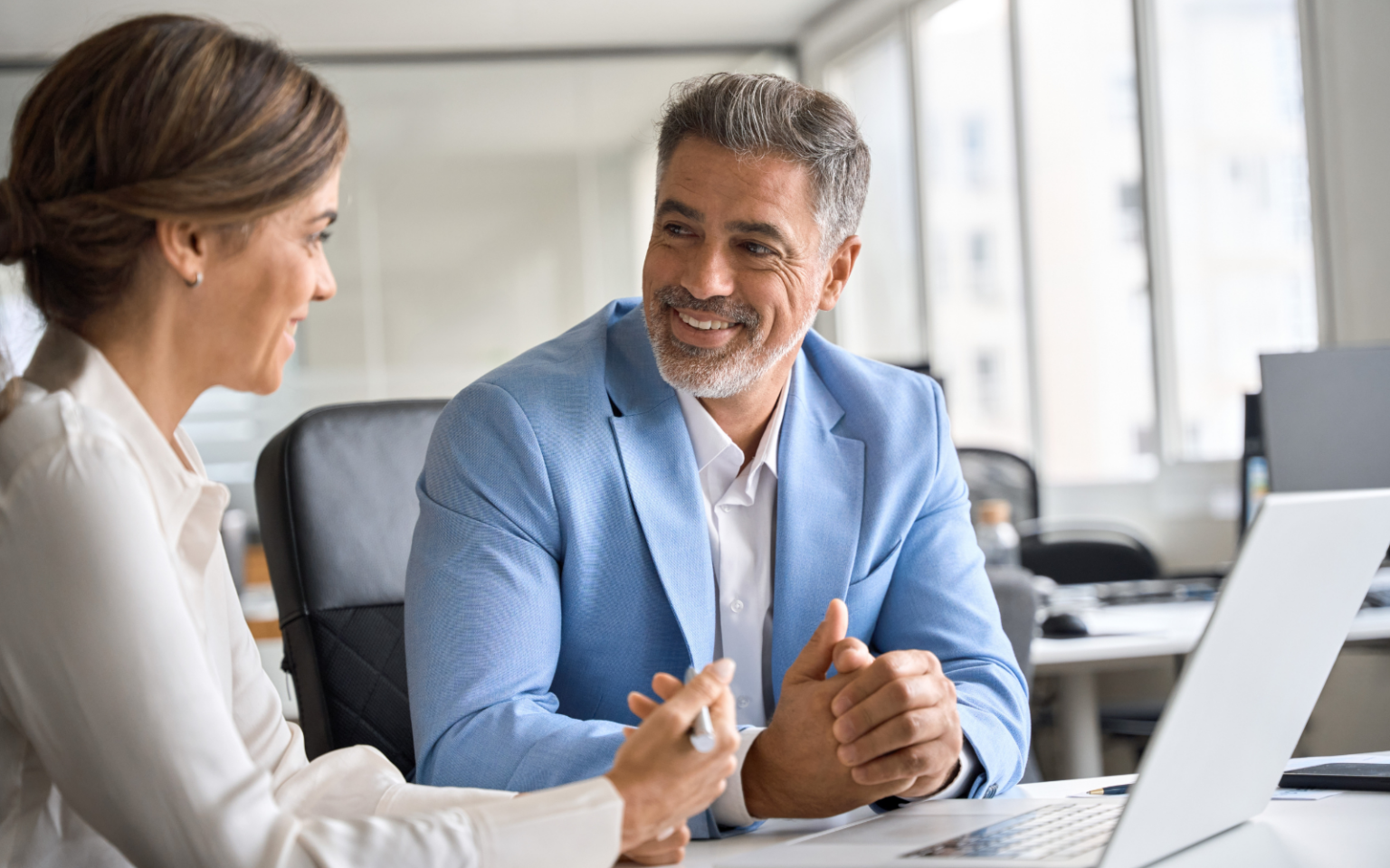 Two business people smiling discussing how to hire an IT manager