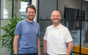 (L-R) Richard Bartlett and Matt Collingwood standing next to each other smiling at the camera, discussing VIQU's investment in Consult Energy.