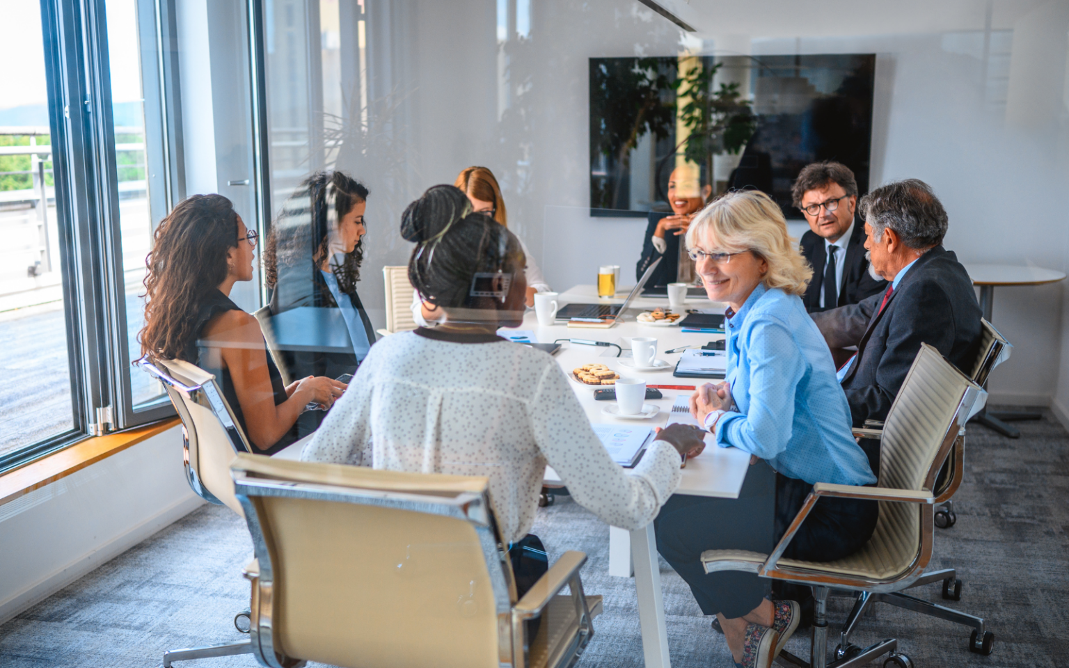 A board of directors in a board room, with one of them discussing with another how they made the transition from tech leader to board member