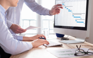 Project Managers looking at a gantt chart having successfully secured a new role after expanding their IT project manager skills